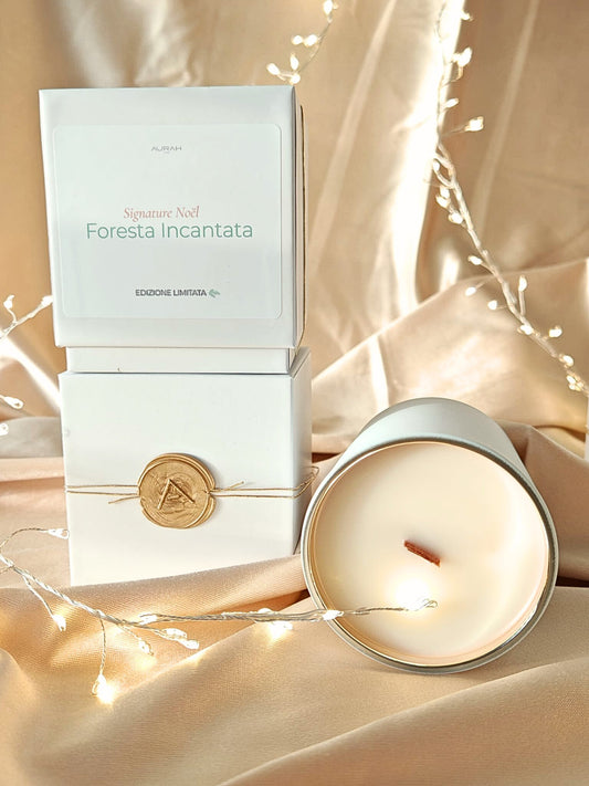 Candela Aurah Lab “Foresta Incantata” in barattolo bianco accanto alla sua scatola con sigillo in cera, fotografata su un set dorato con luci calde e dettagli natalizi