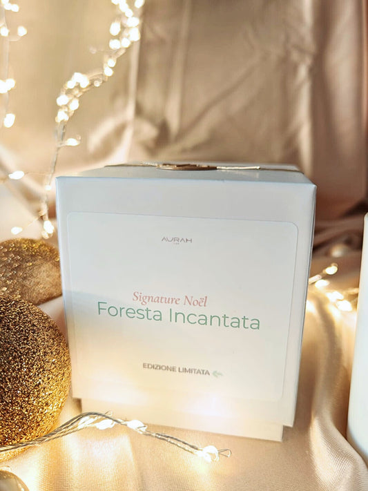 Candela Aurah Lab “Foresta Incantata” in barattolo bianco con sigillo in cera, fotografata su un set dorato con luci calde e dettagli natalizi