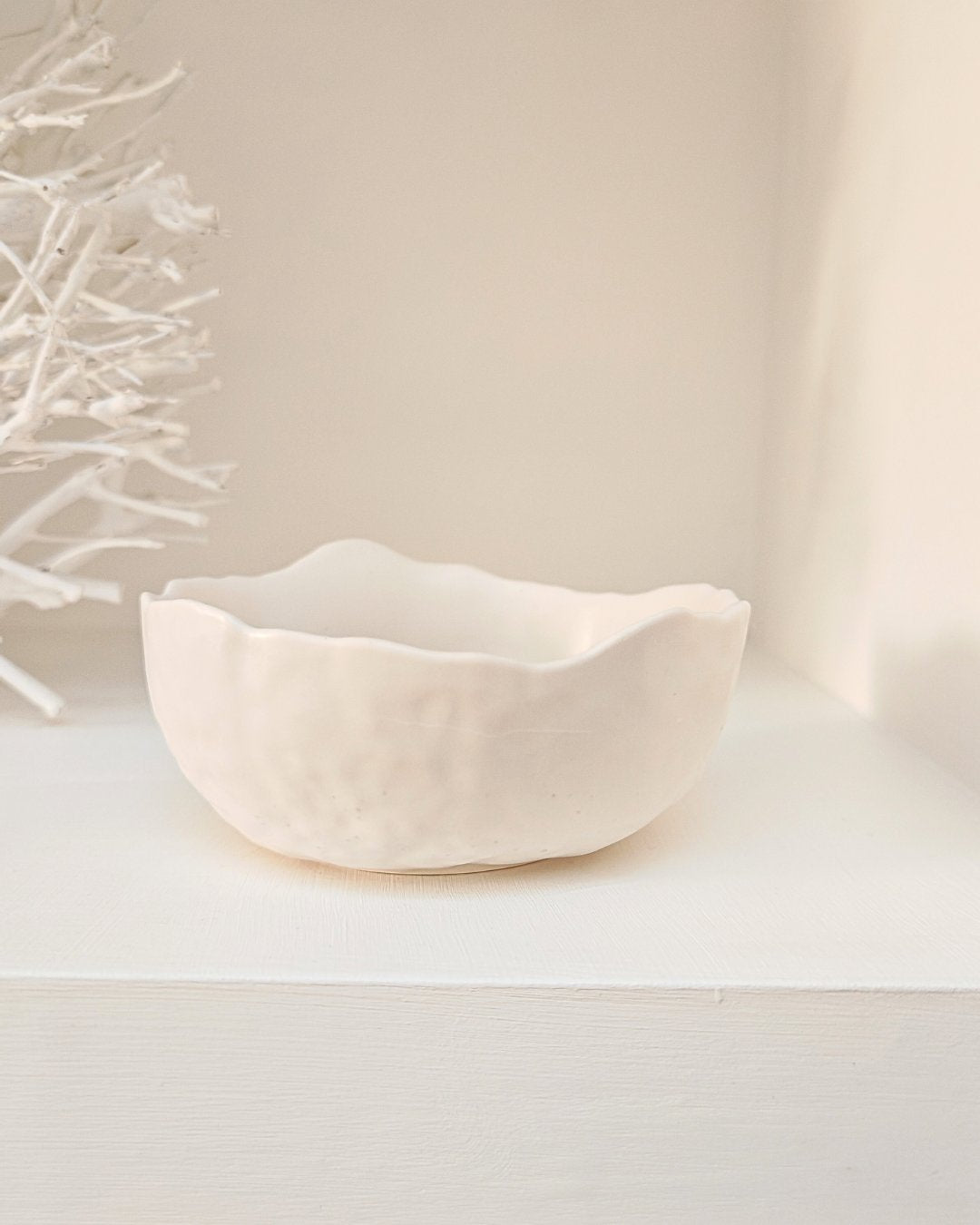 Ciotola decorativa in Jesmonite bianca con bordo irregolare e texture materica creata artigianalmente da Aurah Lab.